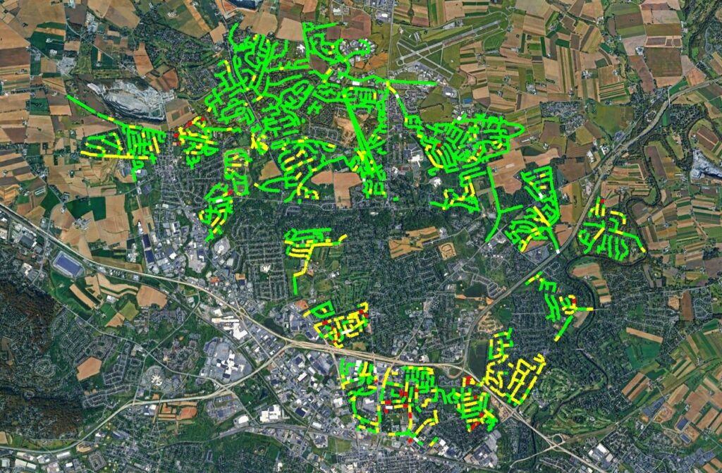 Aerial view of a town showing sewer lines color-coded green, yellow, red, and white to represent blockage conditions.